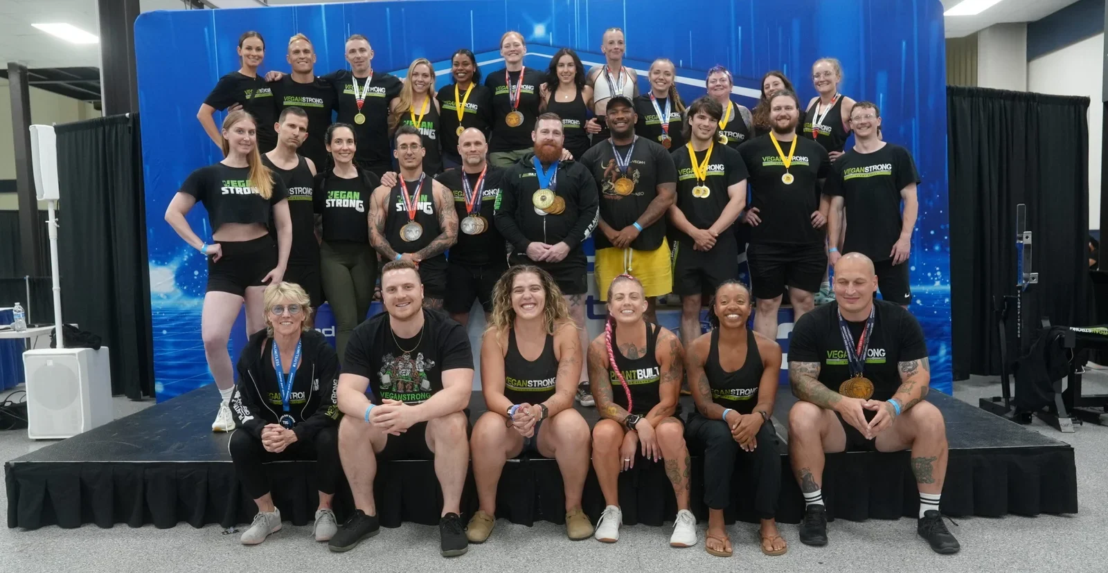 Vegan athletes posing together with Vegan Strong shirts and competition medals